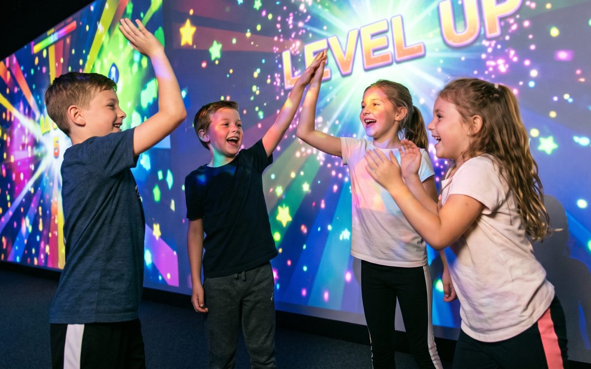 Vier Kinder klatschen sich vor der leuchtenden Wand ab – Level geschafft